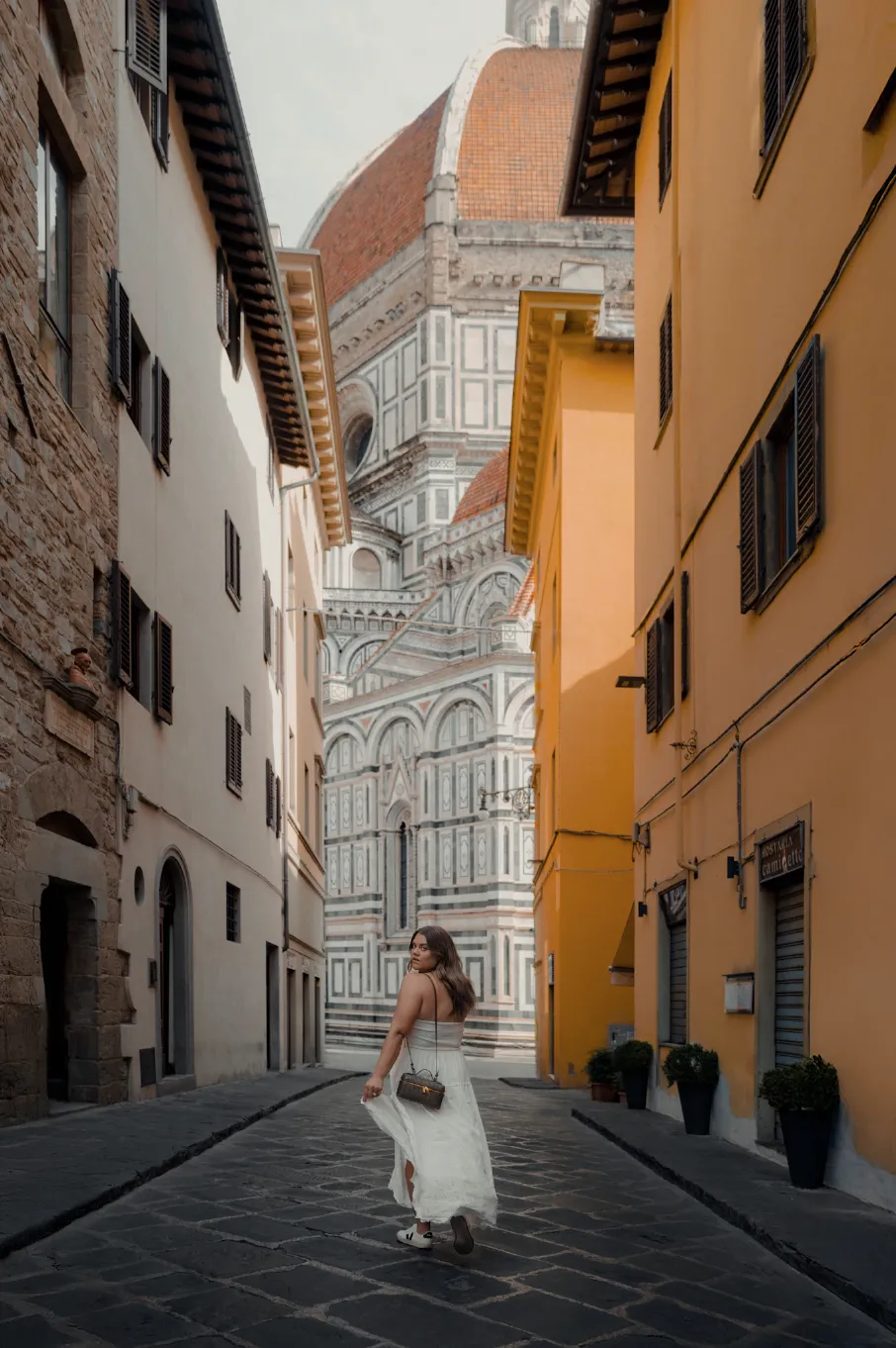Woman walking down a street towards a large cathedral.